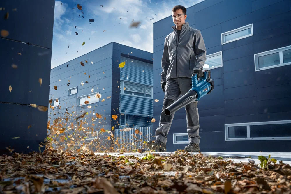 Person entfernt Laub mit Laubbläser